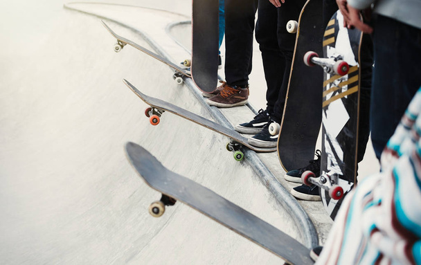 Skaters standing in a line on concrete ramp. Skateboarding contest or competition in outdoor skatepark. Dangerous extreme sport, popular among youth - 写真・画像