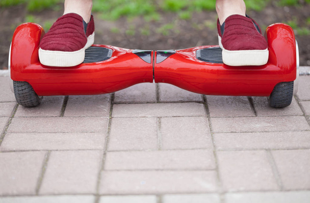 Cllose up on feet of a gir in marsala shoes riding on a modern red electric mini segway or hover board scooter. Trending new transportation technology that is so much fun and easy to ride and produces no air pollution to the atmosphere. - 写真・画像