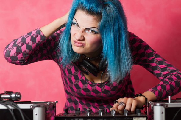 Cute young girl with blue dyed hari and pink outfit playing music records on a professional equipment - Foto, imagen