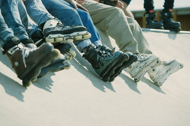Feet of rollerbladers wearing aggressive inline skates standing on top of concrete ramp in outdoor skate park. Extreme sports athlete wearing roller blades for tricks and grinds - Fotó, kép