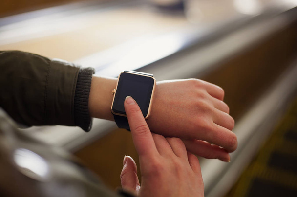 Female using smart watch on her hand while riding escalator stairs in metro. This new gadget lets you always stay connected to internet and social media networks from anywhere you want. - Fotoğraf, Görsel