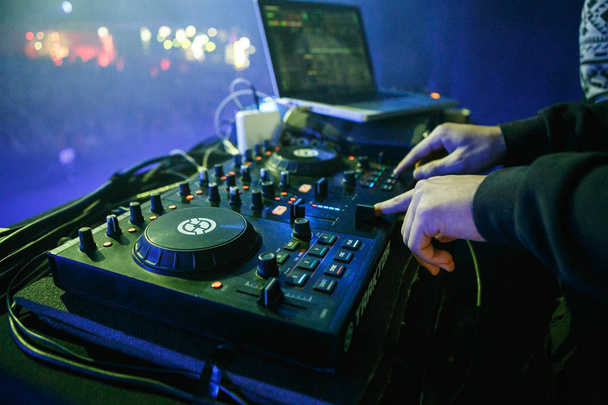 MOSCOW - 30 NOVEMBER,2016: Disc jockey mixing music on digital midi turntable controller at hip hop party on stage in night club. fingers of DJ mixing tracks on mixer on concert in nightclub - Foto, Bild