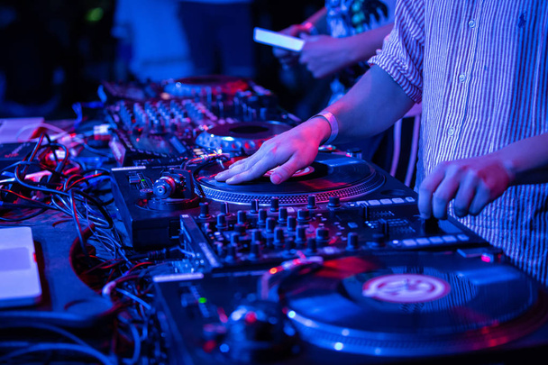 KIEV-11 JULY,2018: Hands of hip hop dj scratching vinyl records on Technics SL-1210 turn table at summer music festival Bazar.Disc jockey scratches record with turntables player in night club - Photo, image
