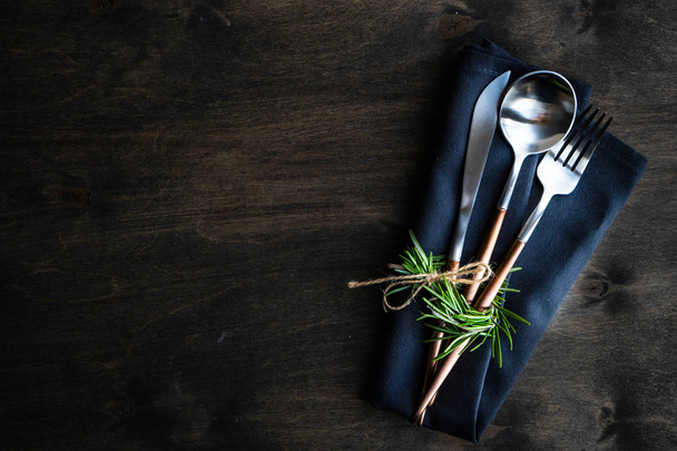 Modern metal cutlery and napkin set with rosemary on dark background with copy space - Fotografie, Obrázek