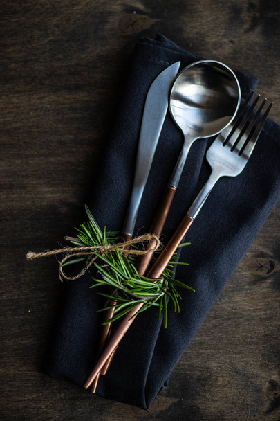 Modern metal cutlery and napkin set with rosemary on dark background with copy space - Φωτογραφία, εικόνα