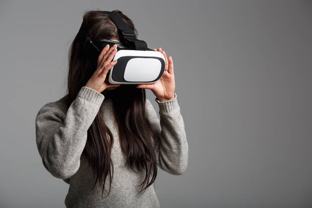 Studio portrait of young white girl enjoying new virtual reality glasses for mobile games apps.Girl use mobile game application with innovative 3d vr headset.Trendy augmented reality gadget play - 写真・画像