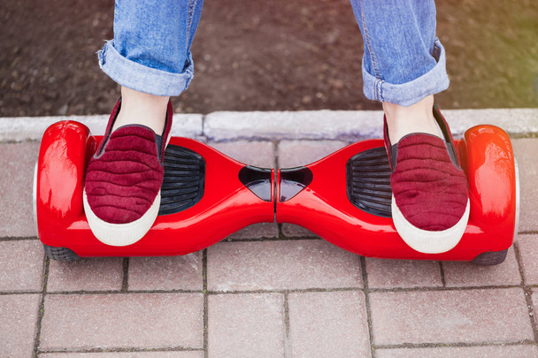  girl in shoes riding on modern red electric mini segway - 写真・画像