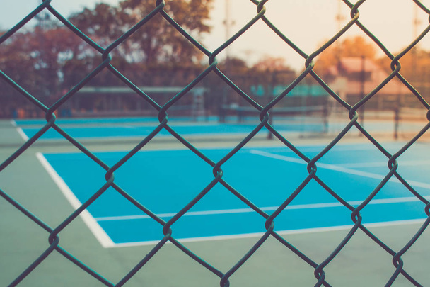Close up metal fence with empty outdoor blue tennis hard court in the background. (Selective focus) - Fotoğraf, Görsel