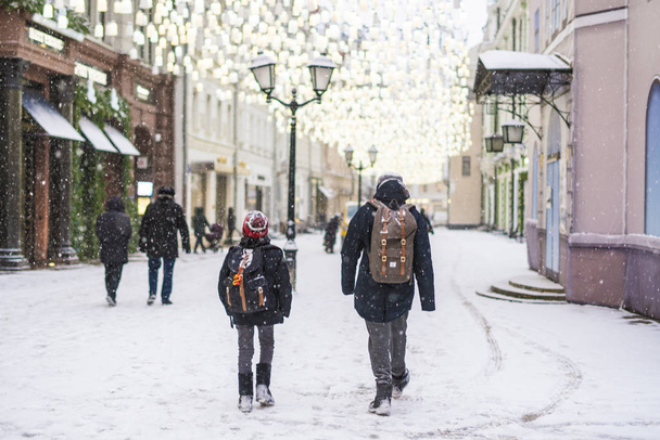dos chicos niños caminan en las calles de la ciudad en temporada de invierno bajo las nevadas
 - Foto, Imagen