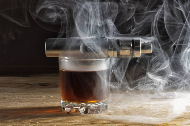 Cigarette électronique couchée sur un verre de brandy enveloppé de vapeur
 - Photo, image