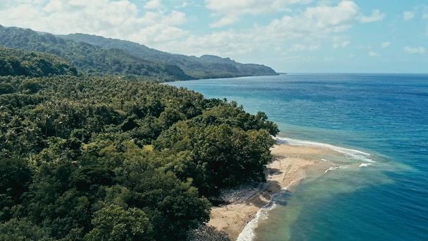 εναέριο κηφήνα εικόνα του ένα απομακρυσμένο νησί της Νοτίου Ειρηνικού ακτή αμμώδης παραλία με όμορφο ωκεανό θάλασσα Θαλασσογραφία και πολύβλαστο τροπικό τροπικό δάσος ζούγκλα με έναν ύφαλο και το ποτάμι - Φωτογραφία, εικόνα