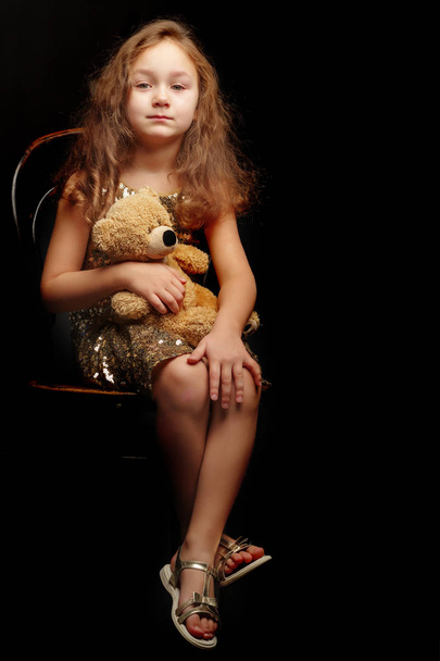 Little girl with a teddy bear on a black background. - Fotoğraf, Görsel