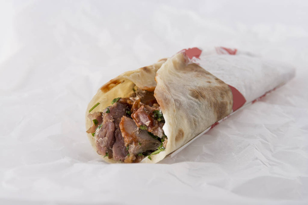 Tasty shawarma sandwich on white paper background - Foto, afbeelding