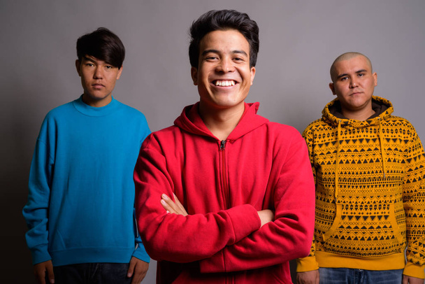 Three young Asian men wearing warm clothing against gray backgro - Foto, Imagen