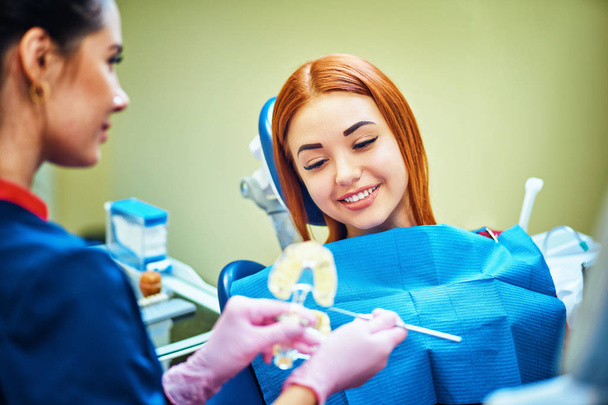 Female dentist showing   patient's artificial jaw at the dental office - Fotó, kép