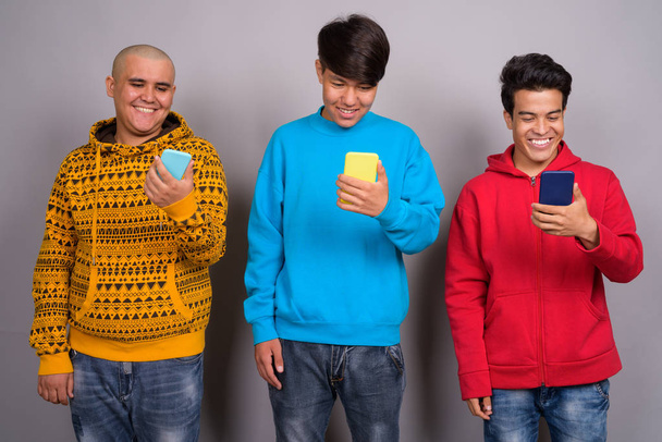 Trois jeunes hommes asiatiques portant des vêtements chauds contre backgro gris
 - Photo, image