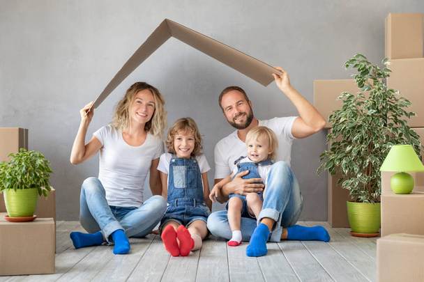 Happy family with two kids playing into new home. Father, mother and children having fun together. Moving house day and real estate concept - Photo, image