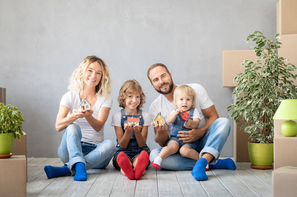 Happy family with two kids playing into new home. Father, mother and children having fun together. Moving house day and real estate concept - Valokuva, kuva