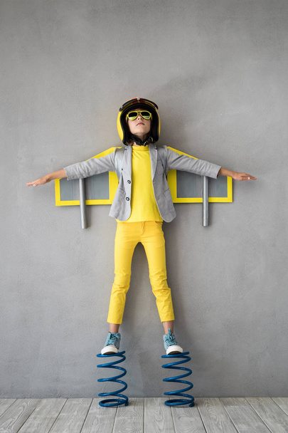 Happy child playing with toy jetpack. Kid pilot standing on spring. Success, innovation and leader concept - Foto, Imagen