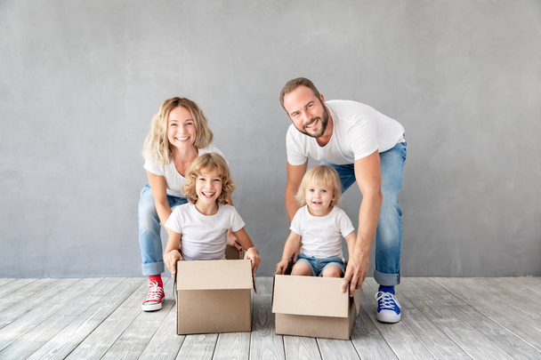 Happy family with two kids playing into new home. Father, mother and children having fun together. Moving house day and real estate concept - Foto, Imagem