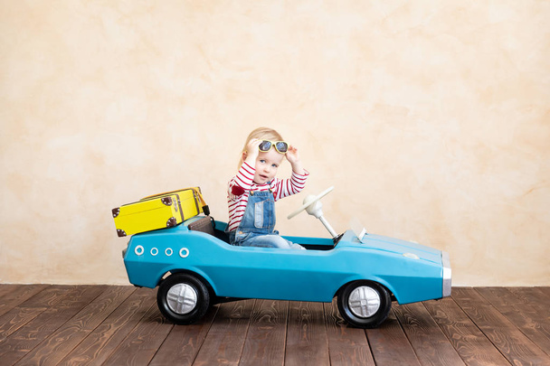 Happy child riding toy vintage car. Funny kid playing at home. Summer vacation and travel concept - Foto, immagini