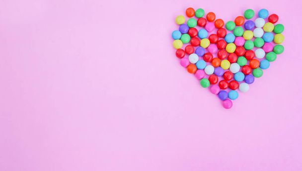 Forma de coração de doces coloridos em rosa
 - Foto, Imagem