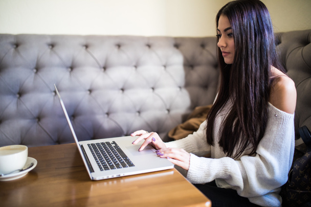 Beautiful woman working while sitting with laptop in modern cafe bar - Photo, Image