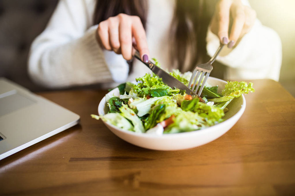 Atrakcyjna kobieta ręka trzyma widelec i łyżka do jedzenia warzyw Sałatka na obiad w kawiarni z bliska. - Zdjęcie, obraz