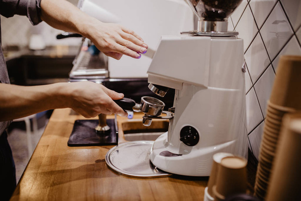 Selected focus on the hands of professional barista pressing coffee using the pounder with wooden handle. - Foto, Imagen