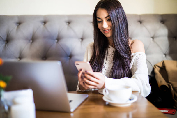 Mulher feliz usando laptop e smartphone no café
 - Foto, Imagem