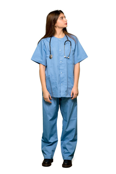 Full-length shot of Young nurse looking up with serious face on isolated white background - Photo, Image