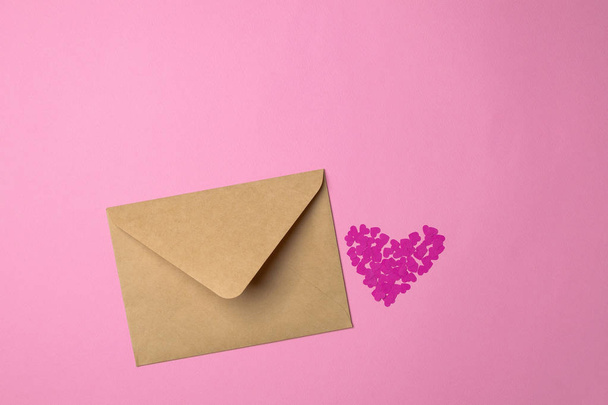 Valentijnsdag minimale concept, liefdesbrief - ambachtelijke envelop roze hart is gemaakt van papier op roze achtergrond - Foto, afbeelding