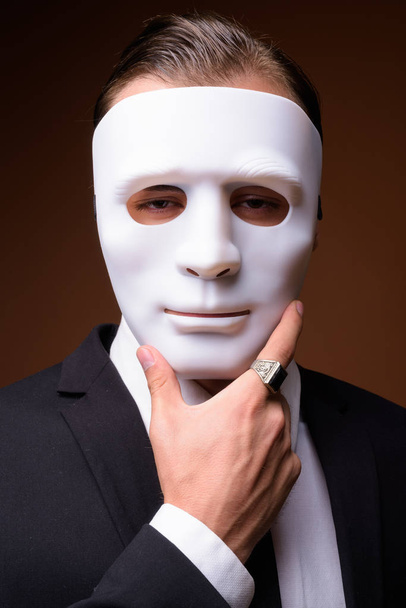 Portrait of young Caucasian businessman wearing white mask - 写真・画像