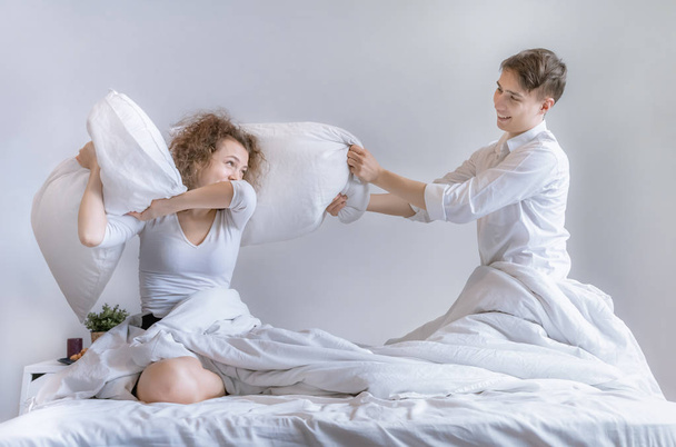 Пары используют подушку, чтобы дразнить друг друга на кровати.
. - Фото, изображение