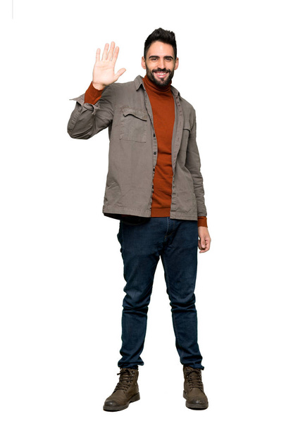 Full-length shot of Handsome man with beard saluting with hand with happy expression on isolated white background - Foto, Imagen