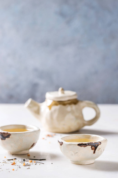 Hot green tea in two traditional chinese clay ceramic cup and teapot standing on white marble table. - Foto, immagini