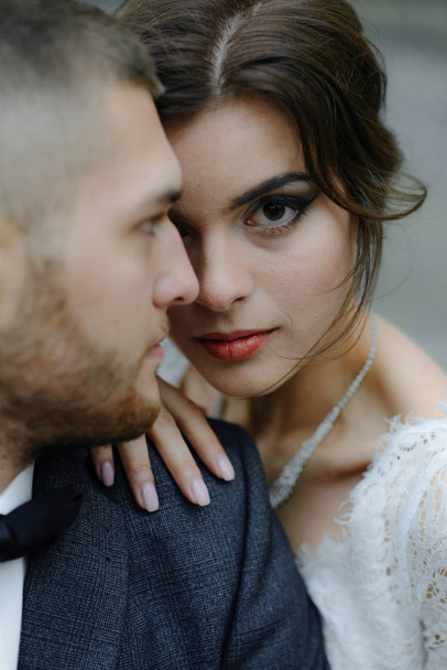 the groom in a gray suit and the bride in a gray dress look at each other, closeup portrait - 写真・画像
