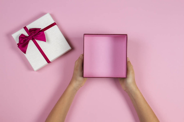 Hands holding open empty present gift box on pastel pink background, top view - Photo, Image