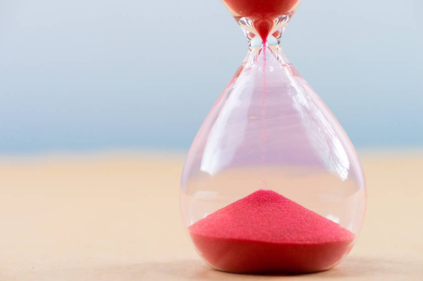 Hourglass with flowing sand on table. Time management - Foto, Imagem