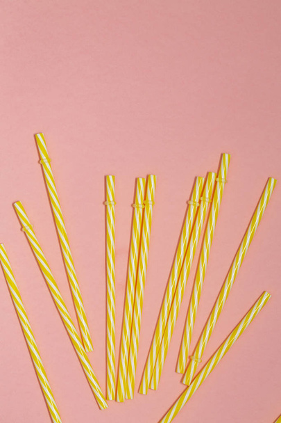 yellow striped straws on pink background - Foto, afbeelding