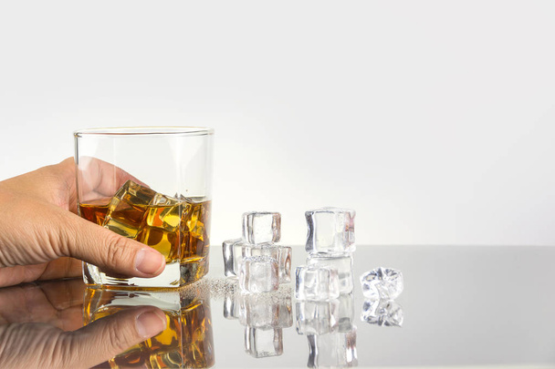 рука держа стакан виски с кубиками льда
 - Фото, изображение