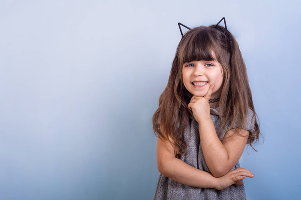 Beautiful female kid in hair hoop with cat ears and fashion clothes against color background. Kawaii, anime and creative advertising concepts. - Photo, Image