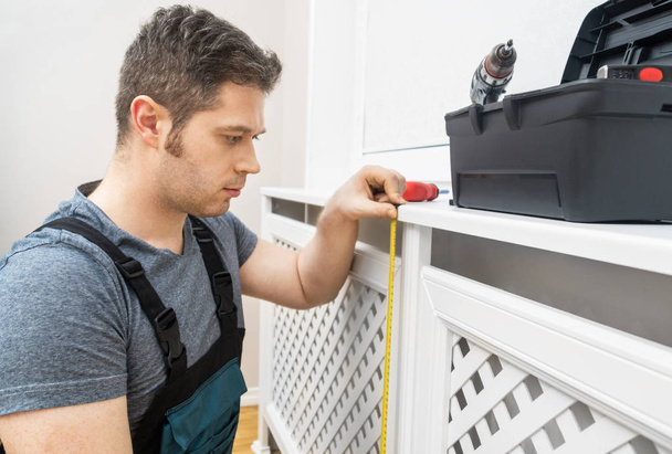 Professionele klusjesman monteren van de radiator kabinet thuis. - Foto, afbeelding