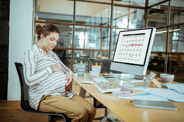Grávida empresária sentindo-se feliz segurando sua barriga grávida
 - Foto, Imagem