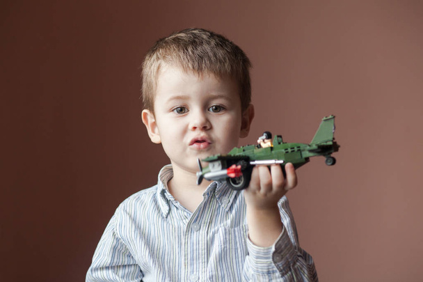 Cute little boy playing with a toy airplane. Military Aircraft LEGO - Zdjęcie, obraz