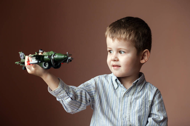 Joli petit garçon jouant avec un avion jouet. Aéronefs militaires LEGO
 - Photo, image