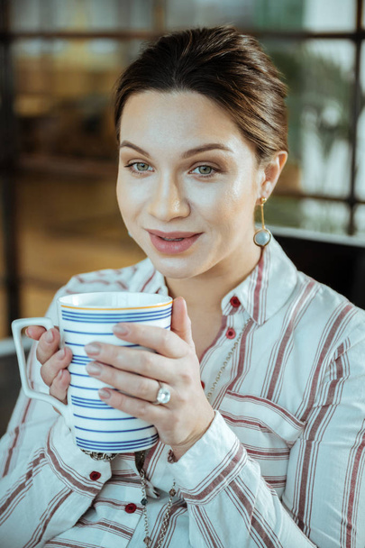Close up of beautiful dark-haired woman holding big cup of tea - Fotoğraf, Görsel