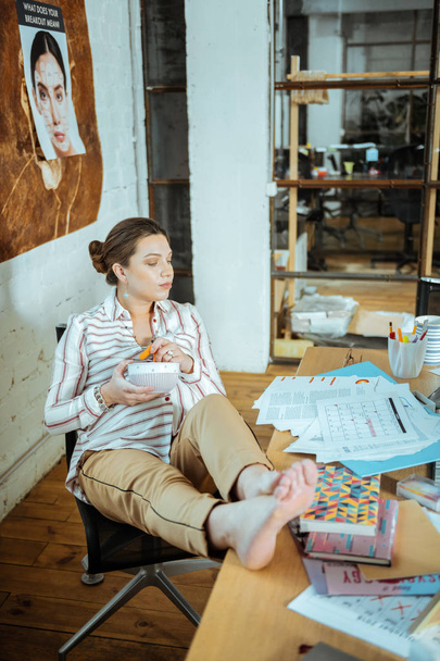 Pregnant woman feeling tired after work eating some carrots - 写真・画像