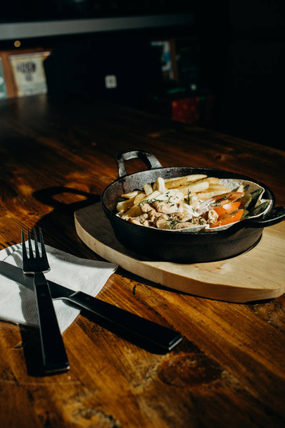 смажену картоплю, смажену курку і овочі в соусі на сковороді, можна зробити виделкою і ножем
 - Фото, зображення