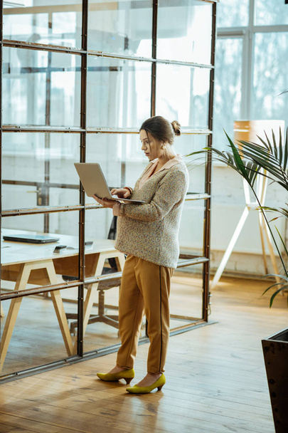 Stylish businesswoman holding her laptop while reading letter - Foto, Imagem